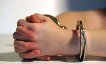 Child's hands in handcuffs resting on table